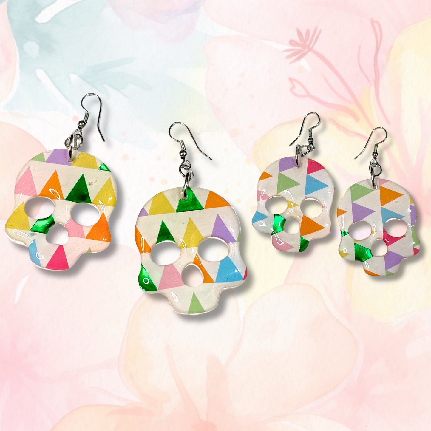 Colorful skull-shaped earrings on a soft, multicolored background