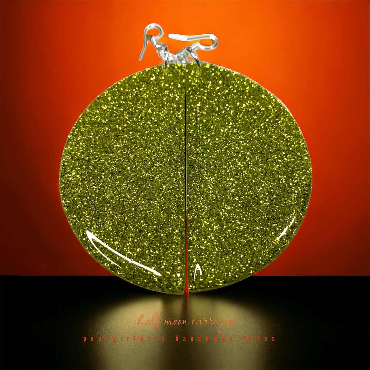 Green glittery earrings on an orange background