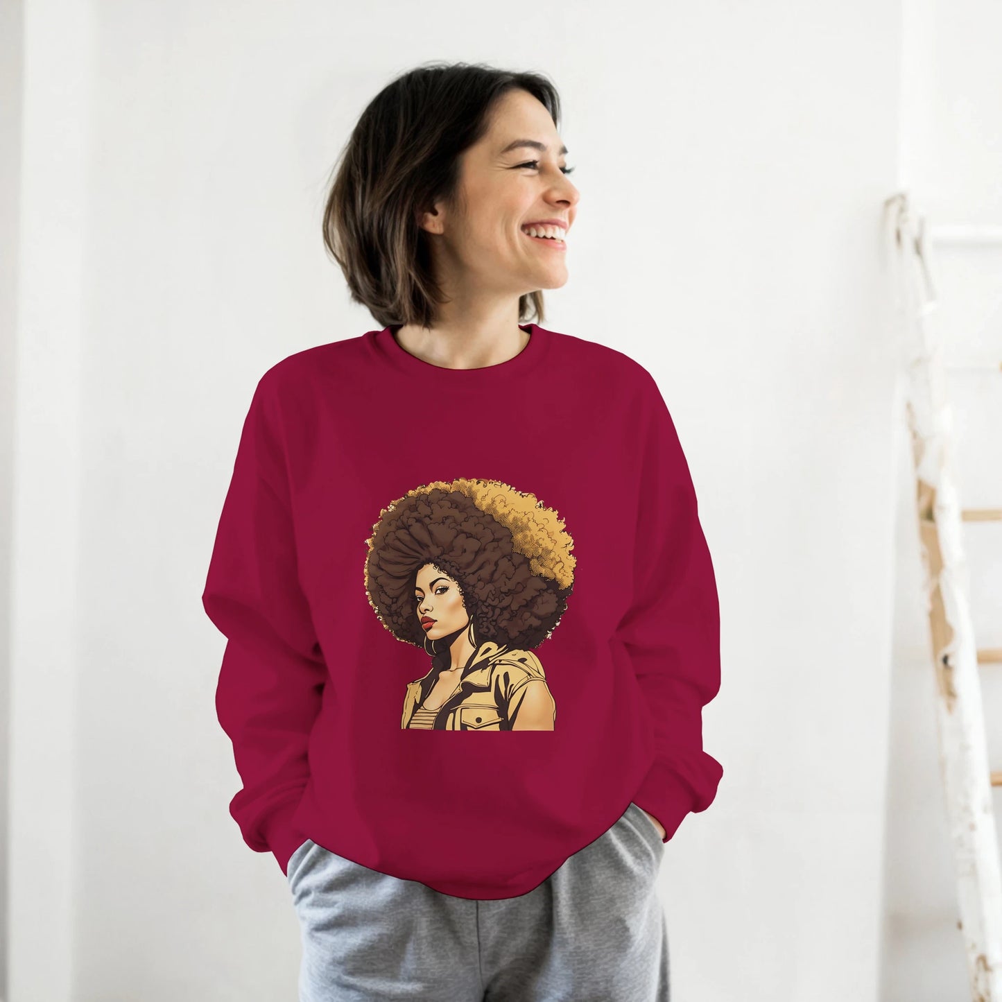 Person wearing a maroon sweatshirt with a graphic design of a woman with an afro on a white background