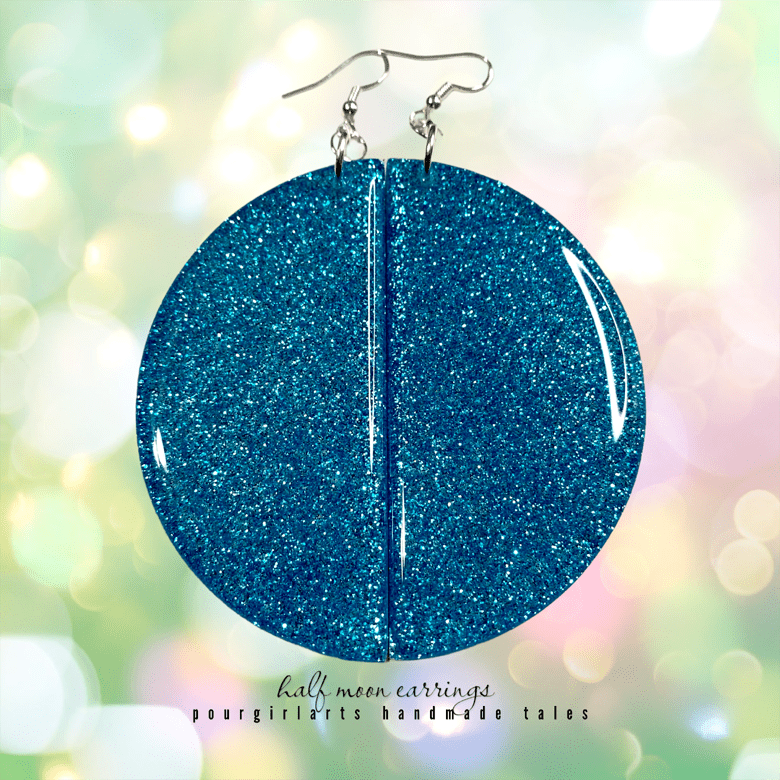Blue glittery circular earrings on a blurred colorful background