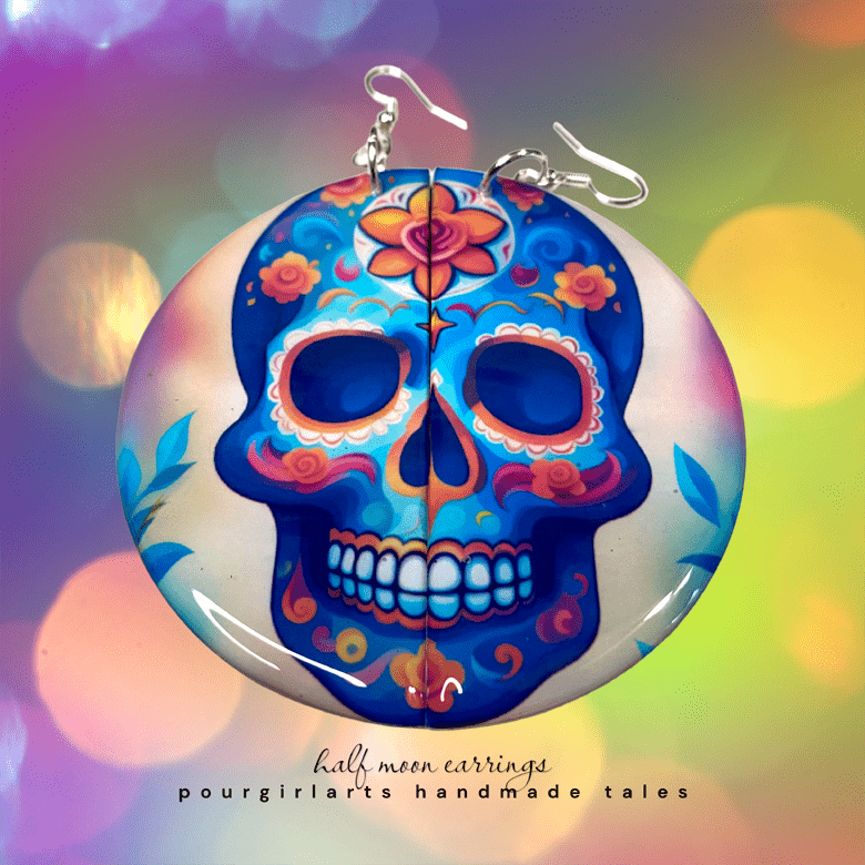 Colorful skull-shaped earrings with floral designs on a colorful blurred background.