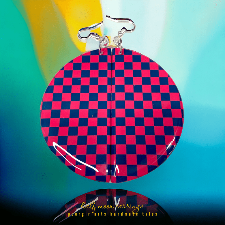 Checkered red and blue earring on a reflective surface with a colorful background