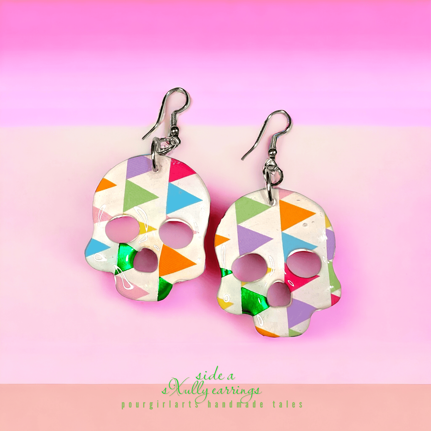 Colorful skull-shaped earrings on a pink background with 'side a' branding.