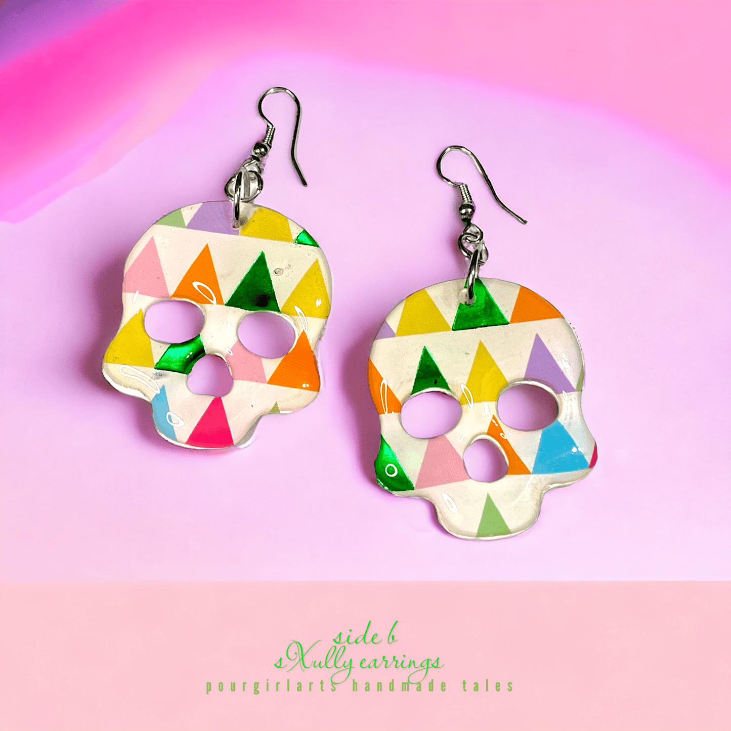 Colorful skull-shaped earrings on a pink background with 'side b' branding.