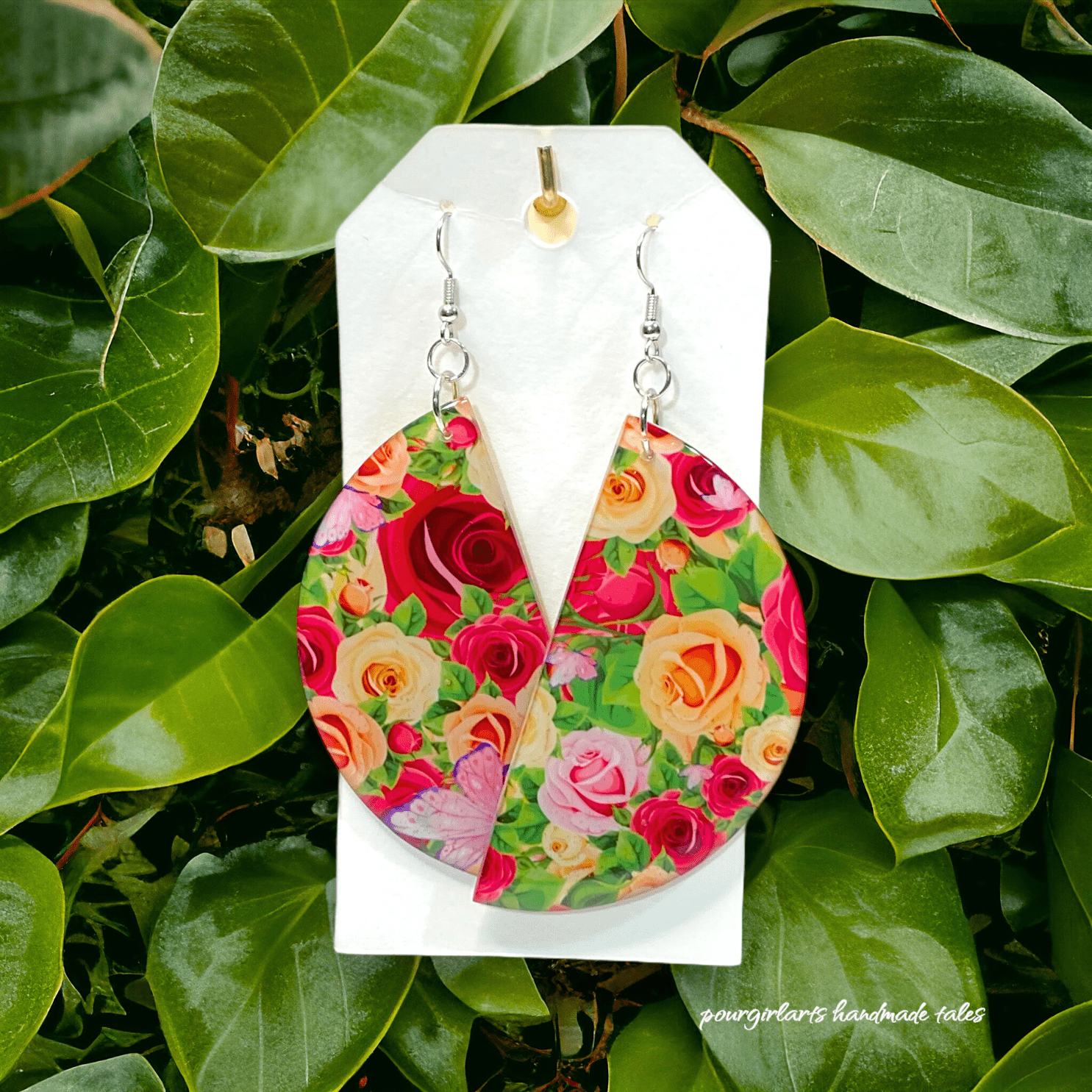 Floral earrings on a white card with green leaves in the background