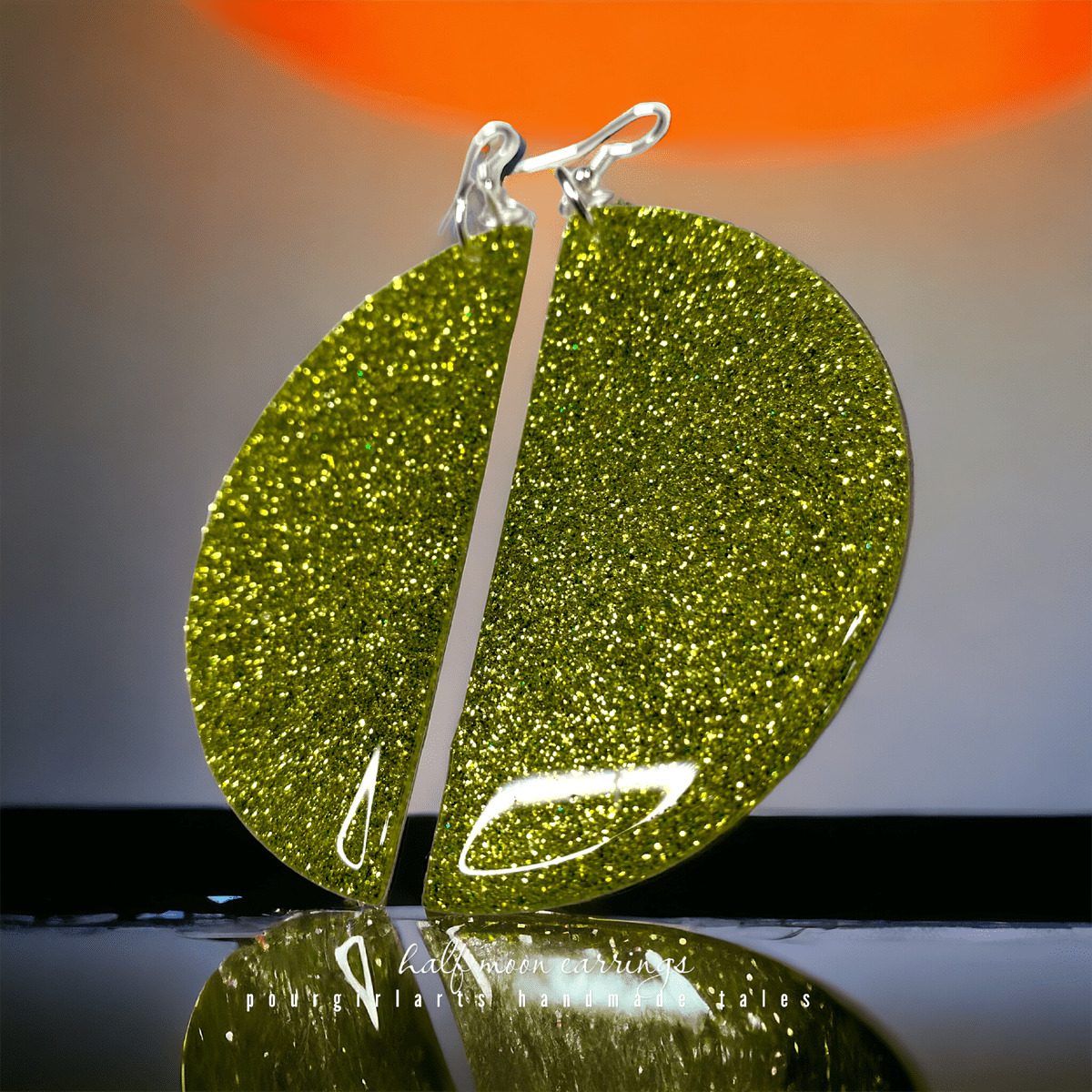 Green glittery circular pendant on a reflective surface with a blurred background