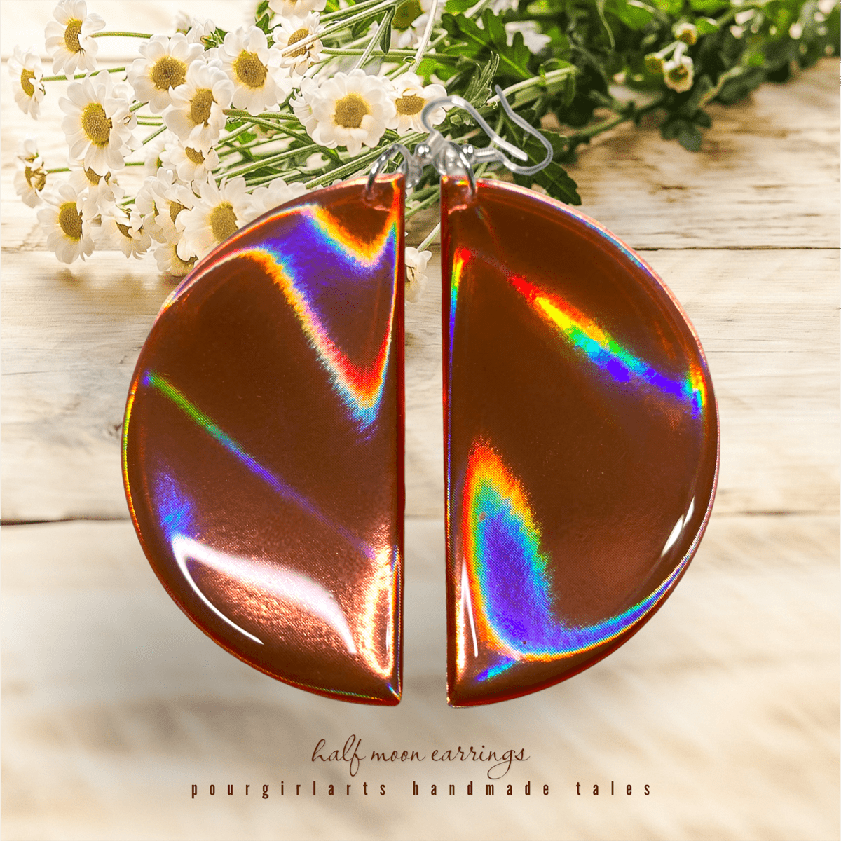 Holographic half-moon earrings on a wooden surface with flowers in the background