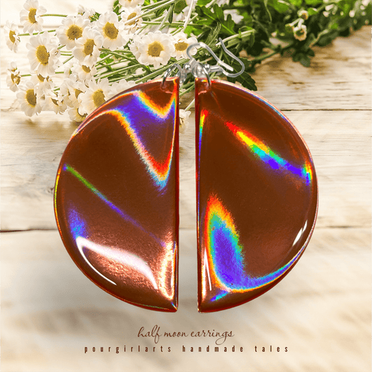 Holographic half-moon earrings on a wooden surface with flowers in the background