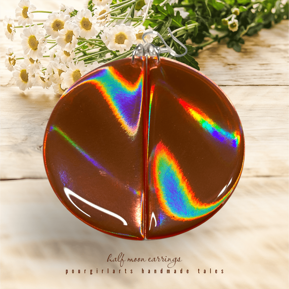 Holographic half-moon earrings on a wooden surface with flowers in the background