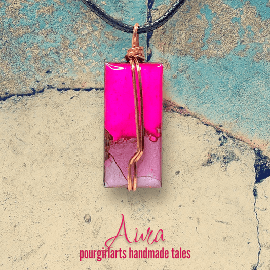 Necklace with a pink pendant on a textured surface, featuring the brand 'Aura'.
