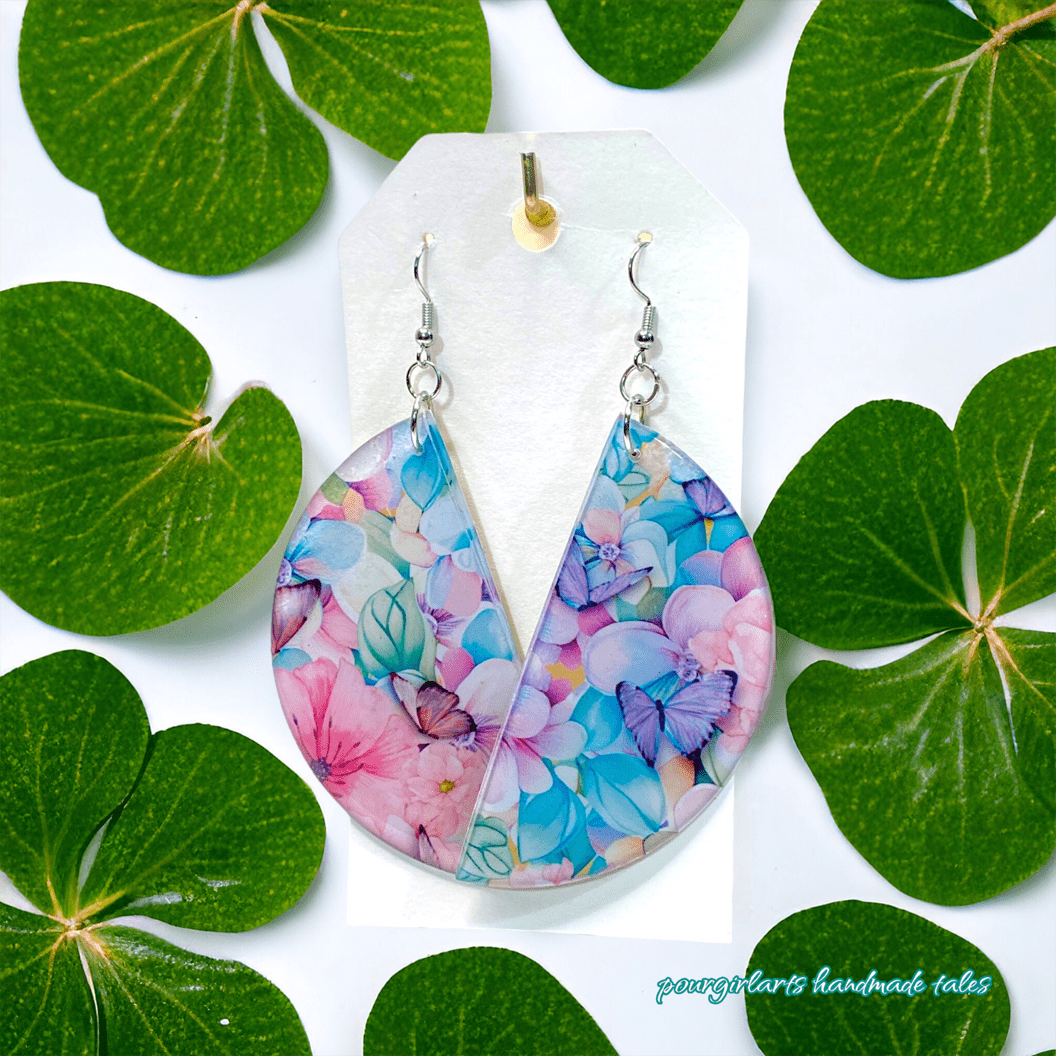 Colorful floral teardrop earrings on a white card with green leaves around