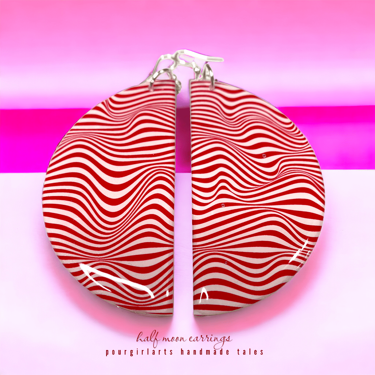 Red and white wavy patterned earrings on a pink background