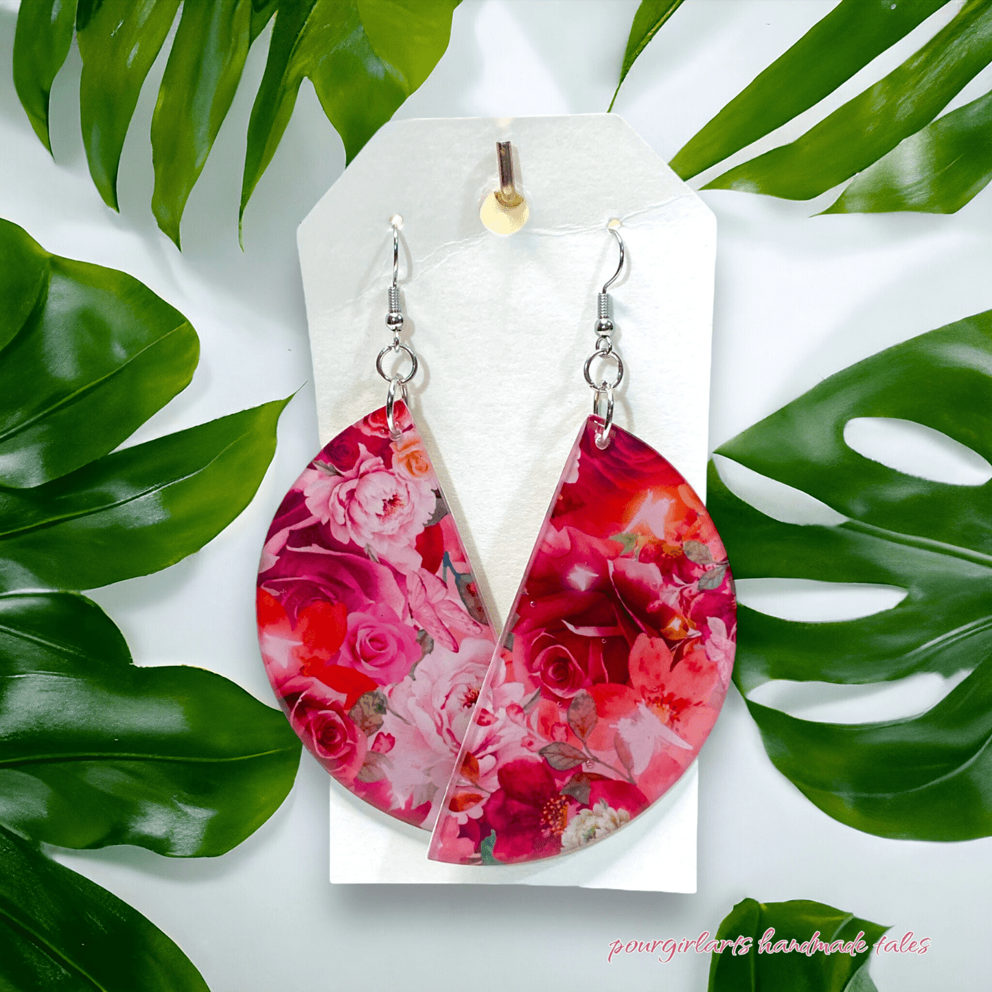 Floral half moon earrings on a white card with green leaves in the background