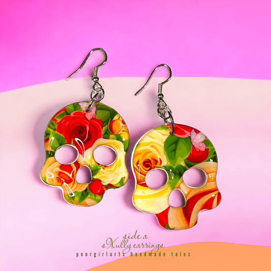 Colorful skull-shaped earrings with floral design on a pink background