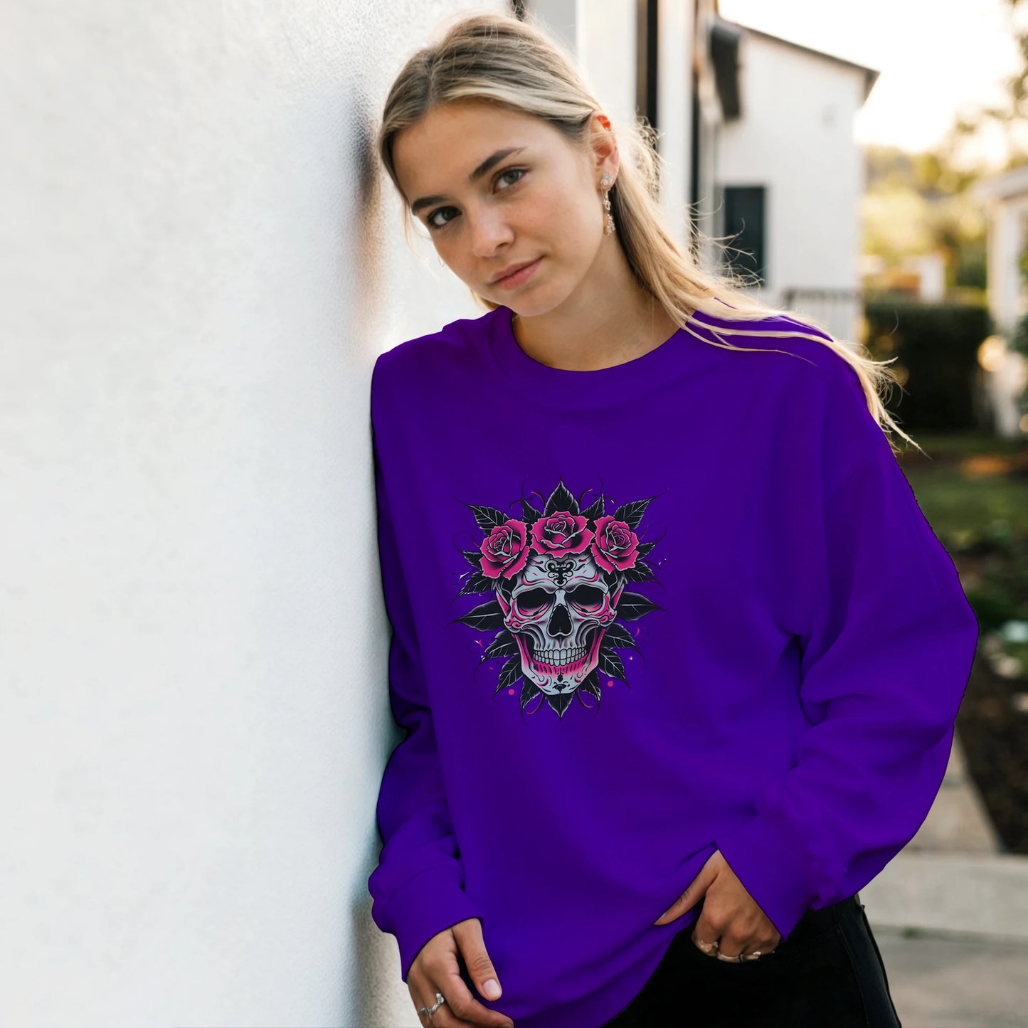 Person wearing a purple sweatshirt with a skull and roses design outdoors.