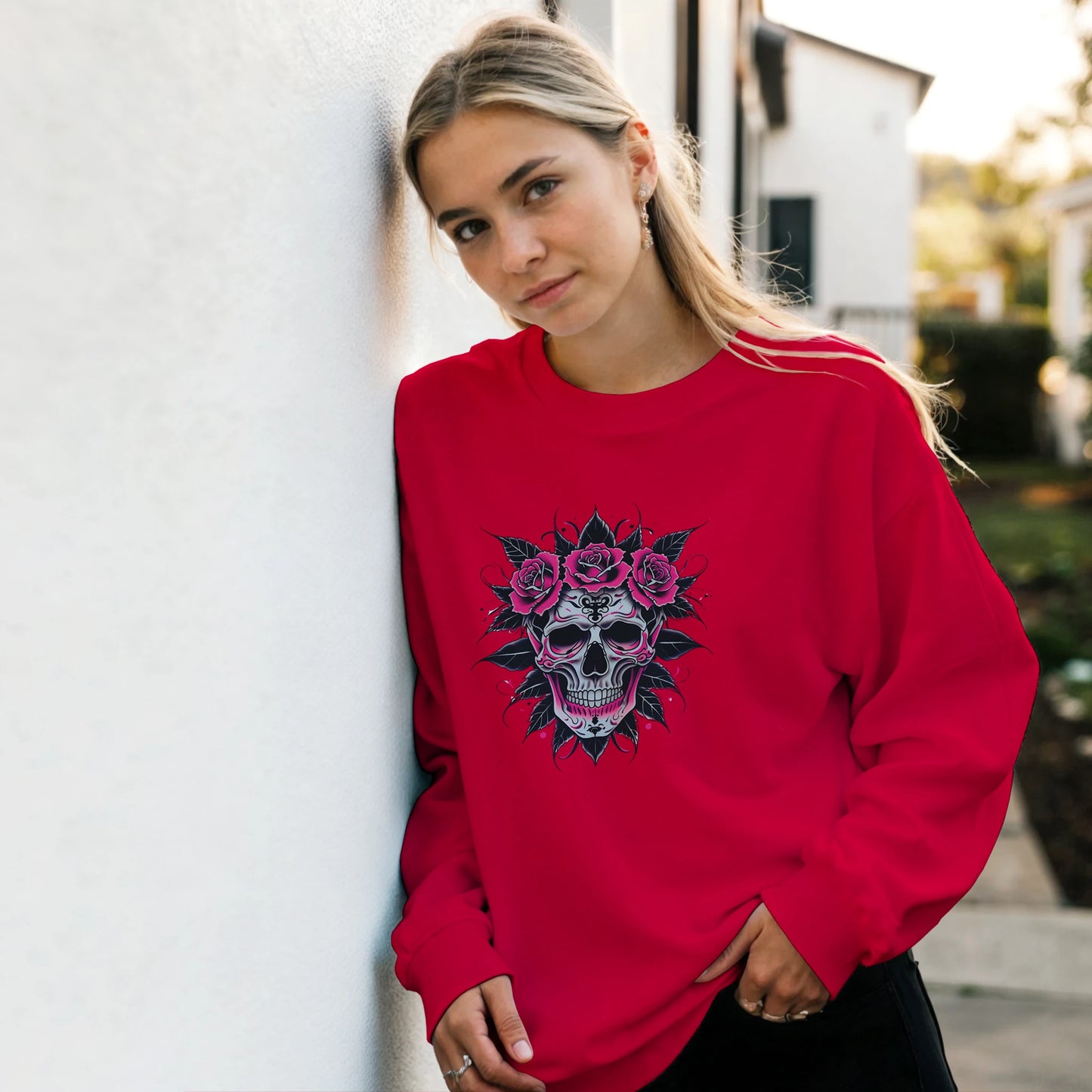 Person wearing a red sweatshirt with a skull and roses design, standing against a light-colored wall.