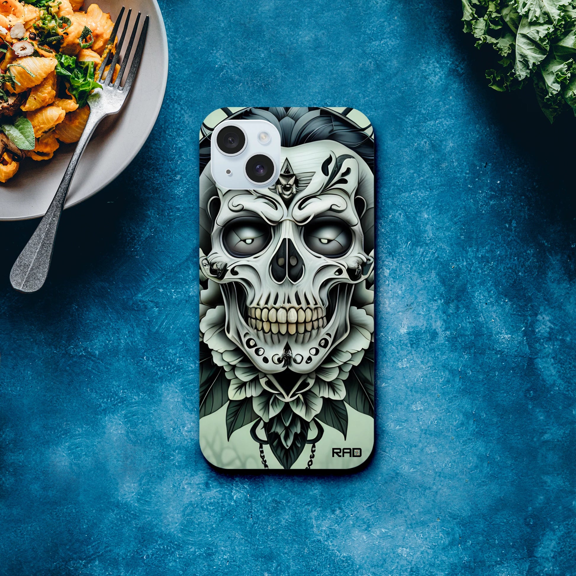 Phone case with skull design on a blue surface with food in the background