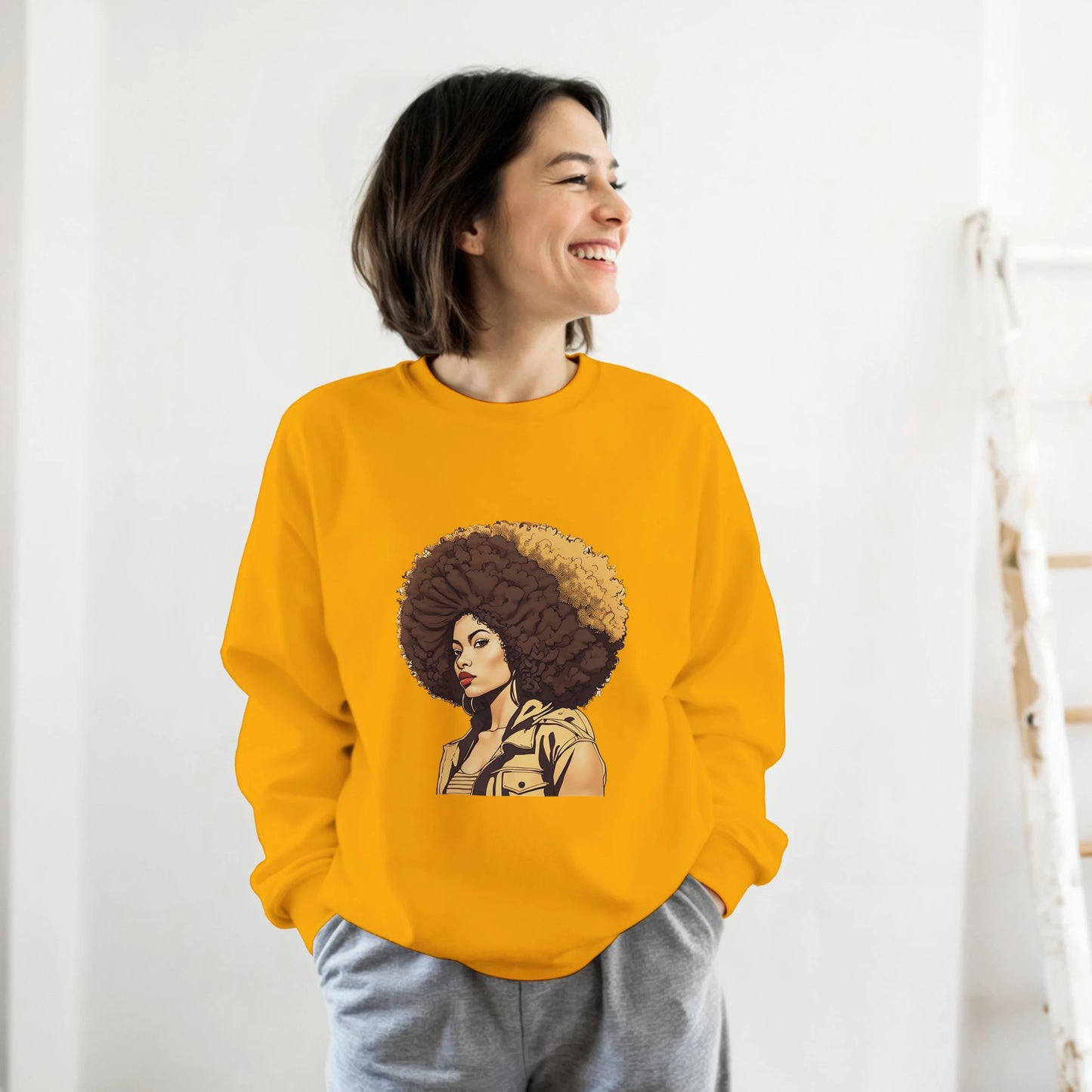 Person wearing a mustard yellow sweatshirt with a graphic design on a white background